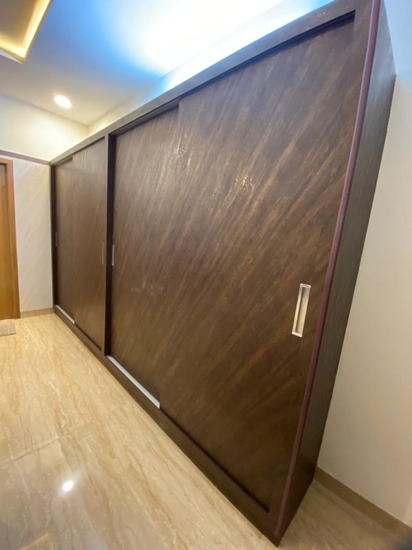 Full-height sliding wardrobe in dark veneer with recessed handles, Coimbatore