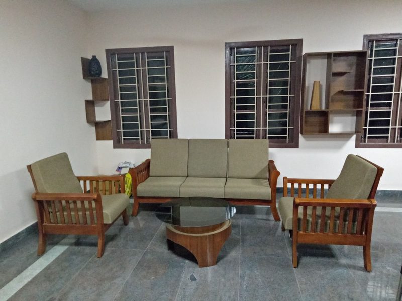 Handcrafted wooden sofa set with cushioned upholstery in a Coimbatore home